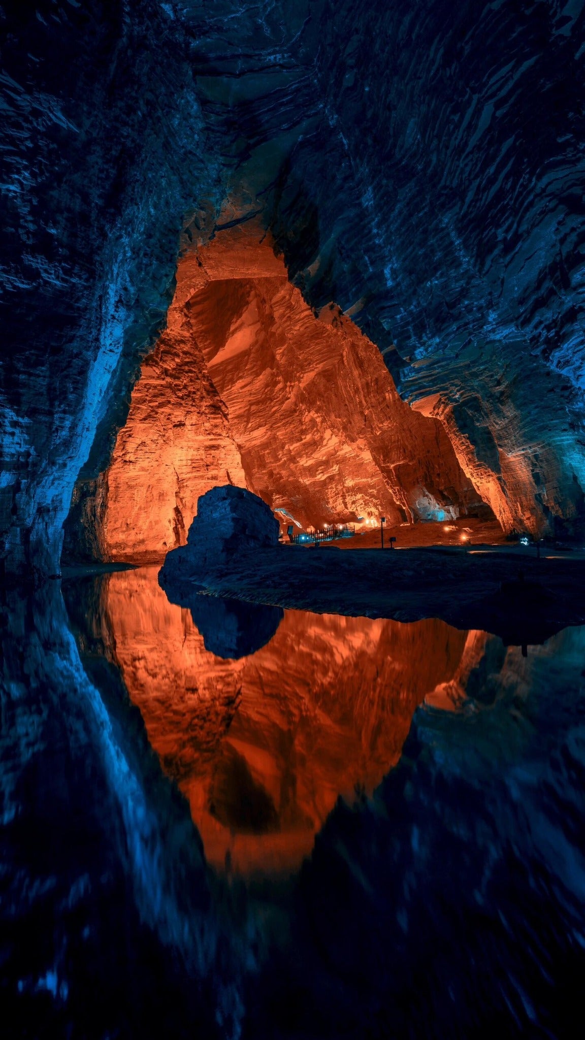 Blue and orange illuminated chamber reflected in water inside Tenglong Cave, Enshi